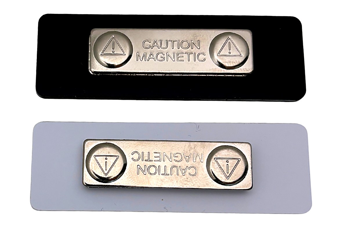 The back of two clear acrylic name tags showing a black and a white protective backing with magnetic fasteners